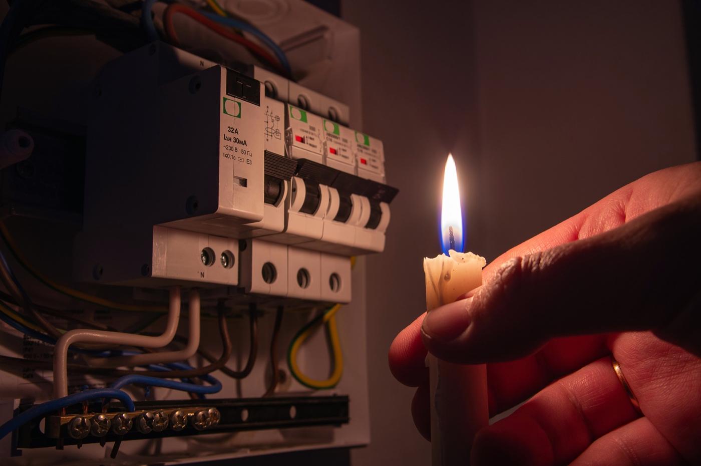 Tablero eléctrico iluminado con una vela durante un corte de luz
